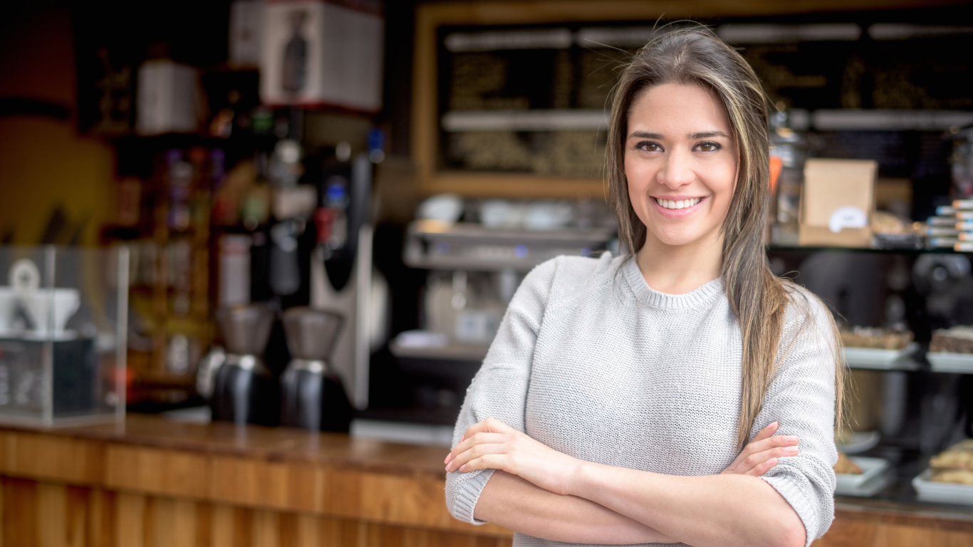 Frau steht mit Freude im eigenen Restaurant